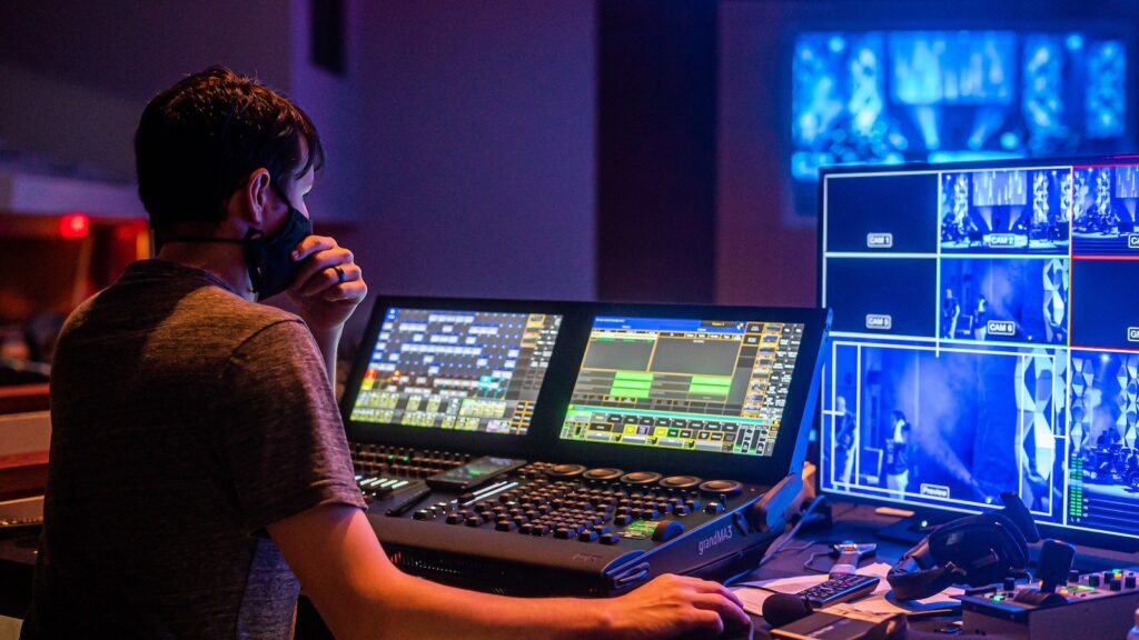 Back view of man in face mask adjusting audio and video on modern equipment during music performance
